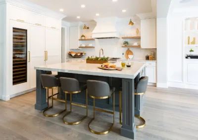 A white kitchen with a center island and bar stools.