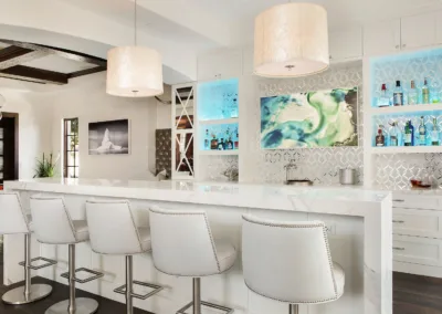 A white kitchen with a bar and stools.